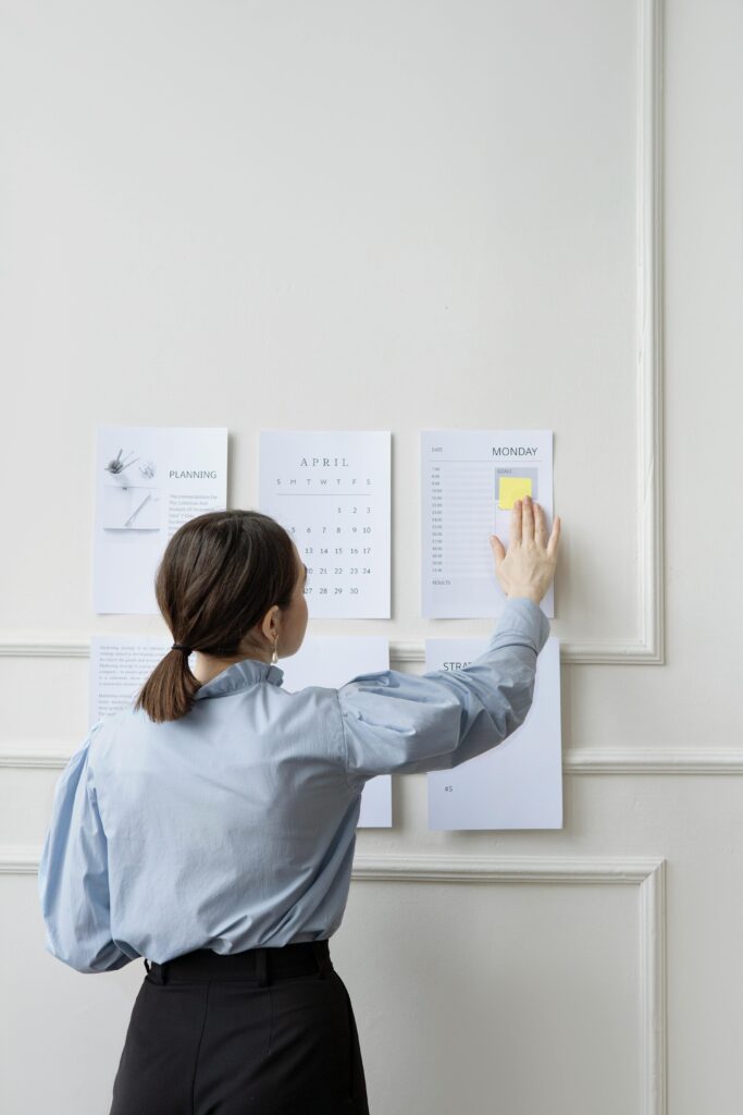 pexels photo 7550893 7550893 Woman organizing wall planner in office showing strategy and planning.